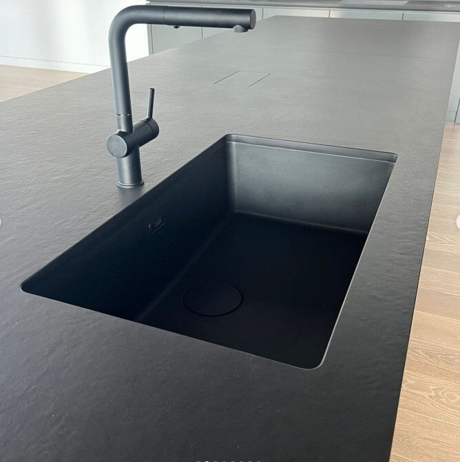 Black textured ultracompact countertop with an integrated sink on a kitchen island