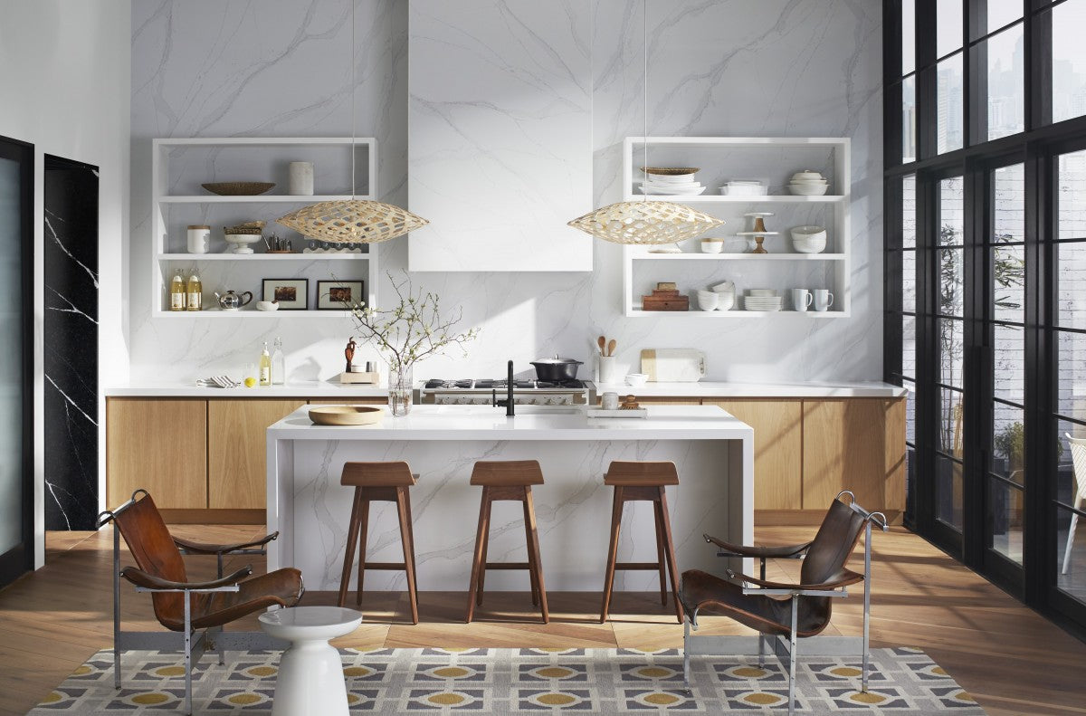 Bright kitchen with a white veined Silestone quartz waterfall island and slab wall, walnut bar stools and leather lounge chairs
