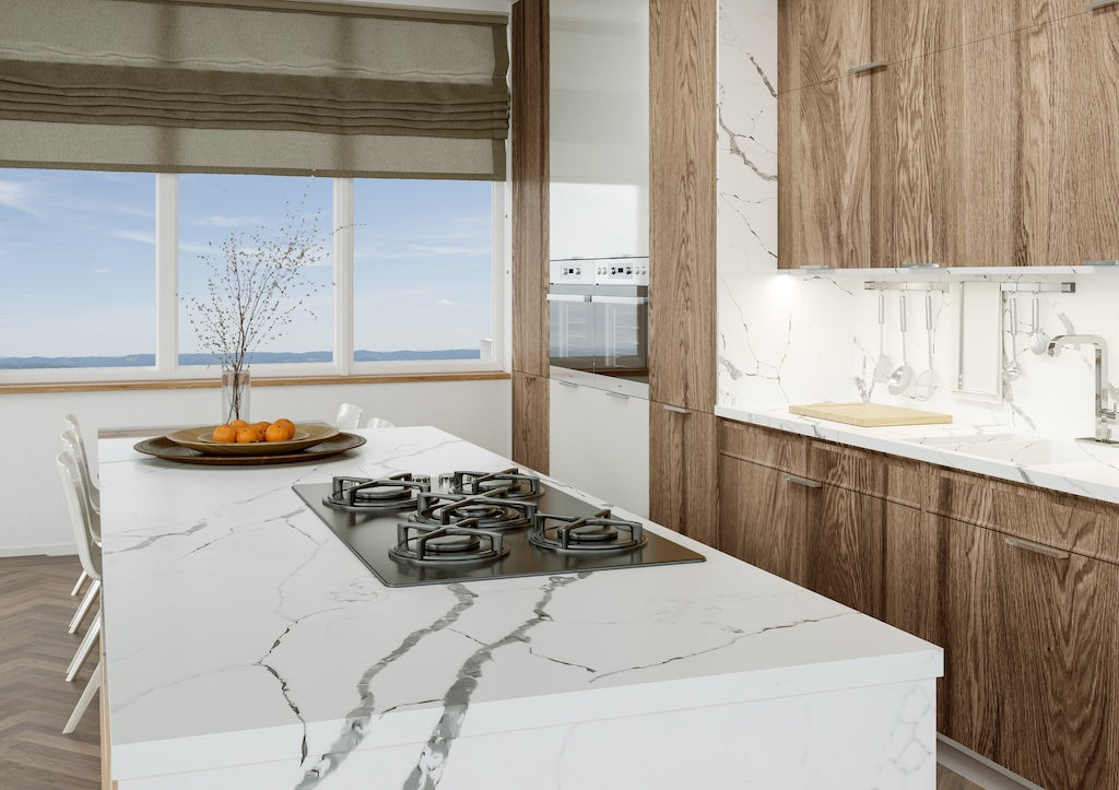 White veined TechniStone quartz island with a built-in gas hob, oak tall units and a sea-view window